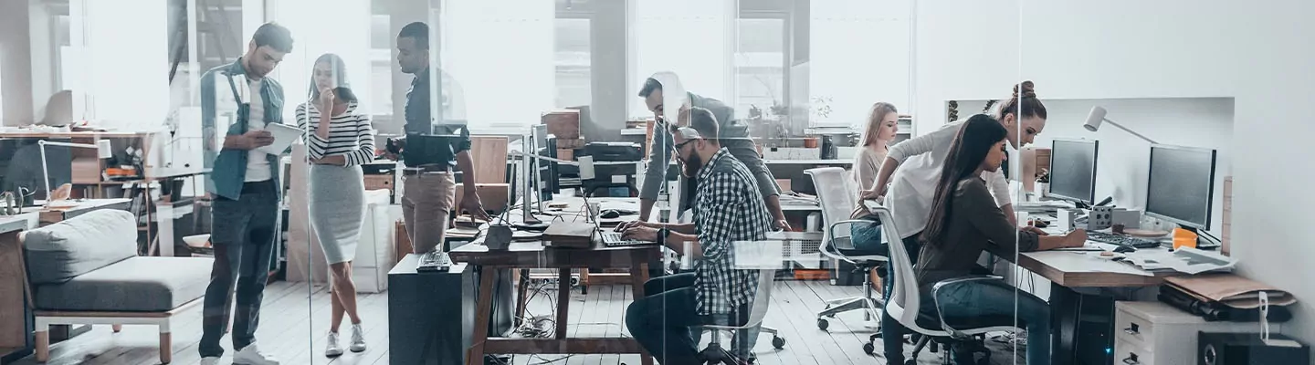 A group of employees working in a bright glass office